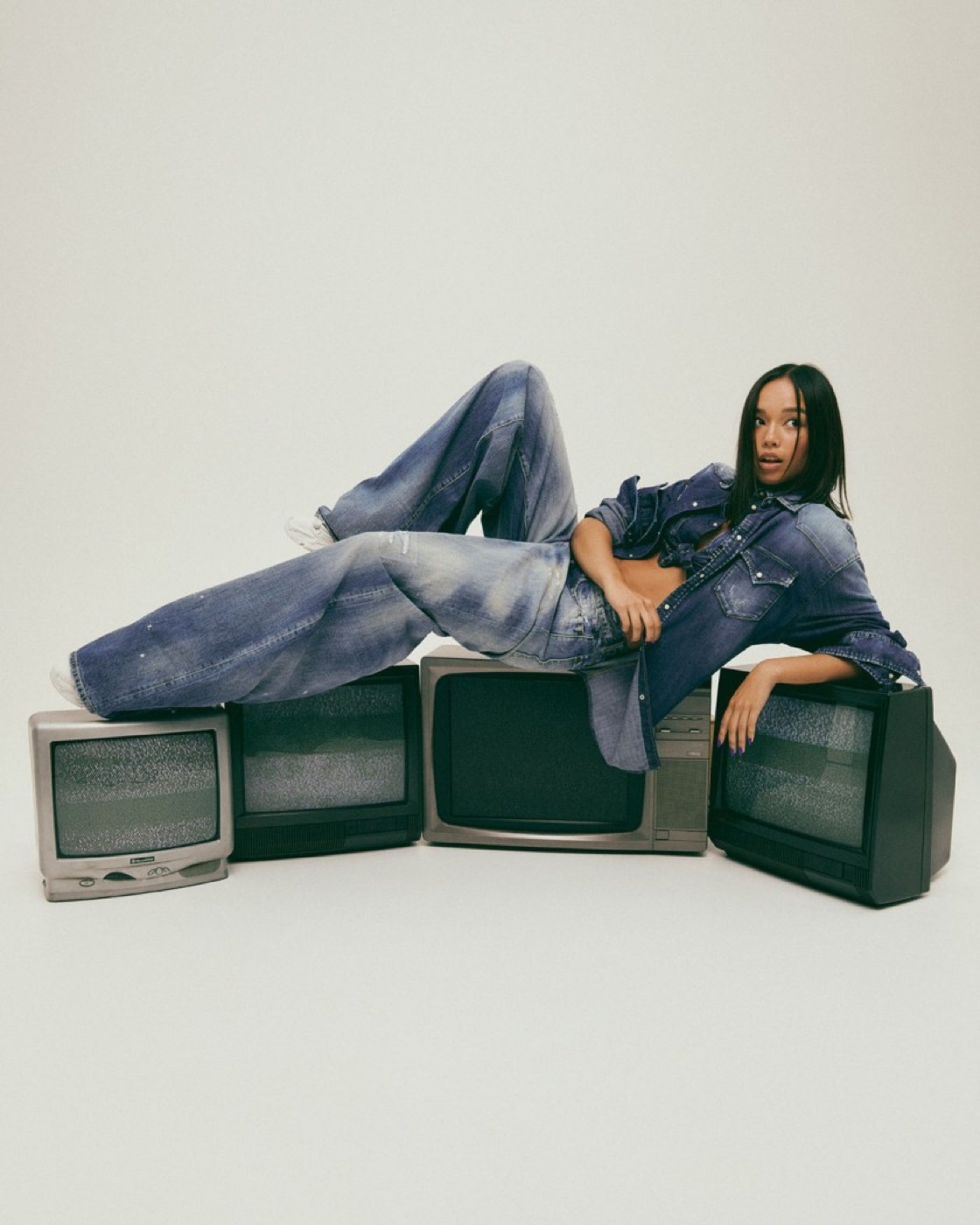 Model reclining in a full denim look across stacked screens